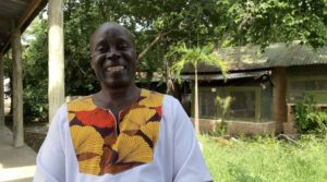 Dr. Oscar Kambi stands in a lush courtyard, smiling.